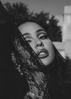 a black and white photo of a woman with long hair wearing a lace veil over her face