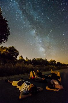 three people laying on the ground under a night sky