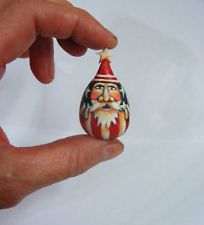 a hand holding a small figurine with a santa clause on it's head