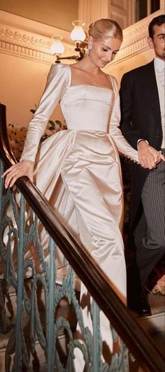 a woman in a white dress is walking down the stairs