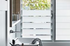 a white sink sitting under a window next to a towel and potted plant in front of it