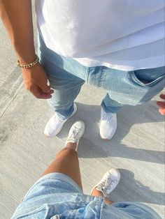 two people standing next to each other with their feet on the ground and one person wearing white shoes