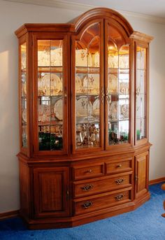 a wooden china cabinet with glass doors on the top and bottom, in a living room