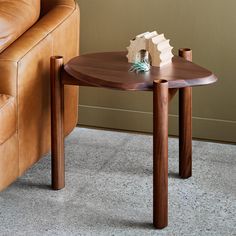 a wooden table sitting on top of a carpeted floor next to a leather couch