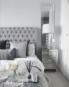 a bedroom with a bed, nightstands and mirror on the wall next to it