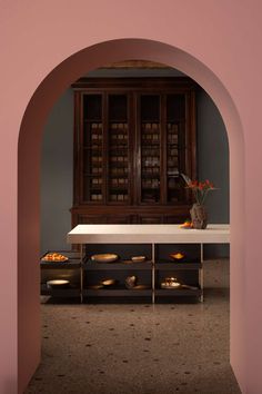 an archway leading into a dining room with wooden cabinets and bowls on the counter top