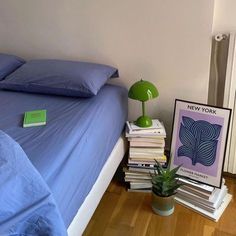 a bed with blue sheets and pillows next to a green lamp on top of it