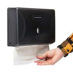 a hand holding a tissue dispenser over a roll of toilet paper