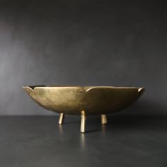 a large brass bowl sitting on top of a black table next to a gray wall