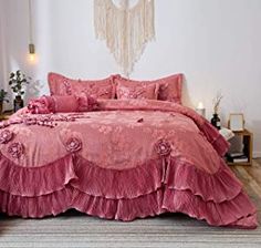 a pink bed with ruffled bedspread and matching comforter in a bedroom