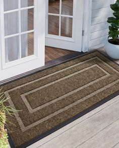 a door mat on the outside of a house with a potted plant next to it