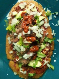 a flatbread pizza topped with meat, cheese and veggies on a blue plate