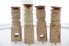 four carved wooden candlesticks sitting on top of a white table next to each other