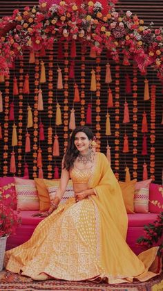 a woman sitting on top of a couch in front of a wall with tassels