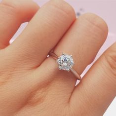 a woman's hand with a diamond ring on top of her finger, showing the center stone