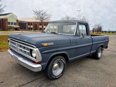 an old blue pickup truck parked in a parking lot