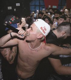 a shirtless man holding a microphone in front of a large group of people at a concert