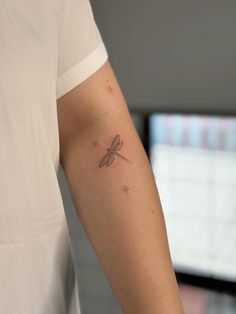 a small dragonfly tattoo on the arm