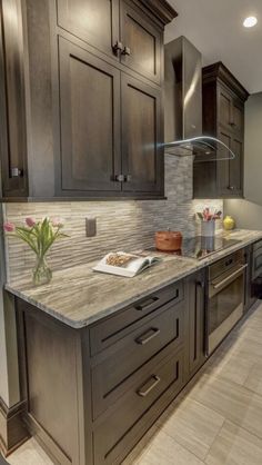 a kitchen with granite counter tops and dark wood cabinetry, along with stainless steel appliances