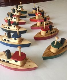 small wooden boats are lined up on a white tablecloth, ready to be used as toys