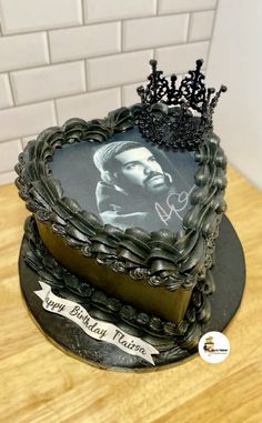 a heart shaped cake decorated with a photo and a tiara on the top, sitting on a wooden table