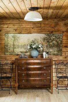 an old dresser and two chairs in a room with wood paneling