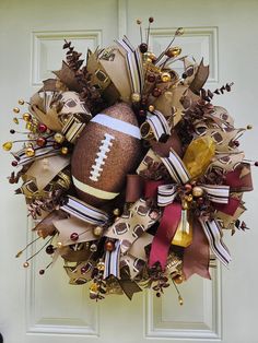 a football wreath is hanging on the front door with ribbons and decorations around it's edges