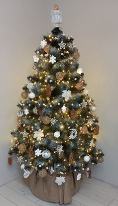 a small christmas tree in a room with white and gold decorations on it's branches