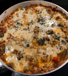 a casserole dish with cheese, meat and vegetables in it sitting on a stove