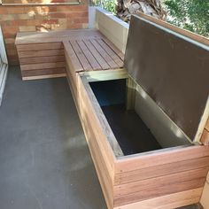 a wooden bench sitting on top of a patio next to a brick wall and tree