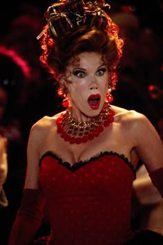 a woman in a red dress is making a face with her mouth open and wearing gloves