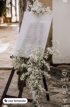 an easel with flowers on it sitting in front of a sign