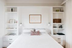 a bedroom with white walls and built in shelving