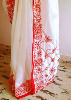 "Stunning half white semi silk saree with intricate all over embroidery and semi raw silk unstiched blouse in reddish orange. The red color thread embroidery is simply stunning aginst offwhite. The entire embroidery is hand worked and the floral border extends more in the front, pallu and the pleats. Saree length 5.5 meters Blouse fabric 1 meter 44\" wide Saree ships in 2-3 days of payment. Delivery within 4-5 days of shipment all over the world. We also offer blouse and petticoat stitching for White Silk Traditional Wear With Floral Embroidery, Unstitched White Blouse Piece With Chikankari Embroidery, White Chikankari Embroidery Blouse Piece Unstitched, Unstitched White Chikankari Embroidery Blouse Piece, Red Traditional Wear With Floral Embroidery, Unstitched White Blouse Piece With Cutdana, Off White Chanderi Traditional Wear With Floral Embroidery, Off White Traditional Wear With Floral Embroidery In Mulmul, Unstitched White Blouse With Resham Embroidery