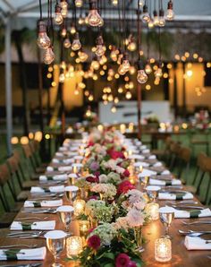 a long table with candles and flowers on it is set up for an outdoor dinner