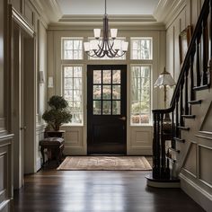 an entryway with stairs, chandelier and potted plant in the center