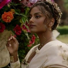 a woman with flowers in her hair is holding onto a flower pot and looking off to the side