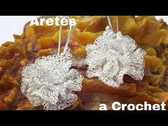 two silver earrings sitting on top of a pile of rocks with the words artes at crochet