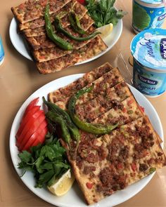 two plates filled with food sitting on top of a table next to cans of water