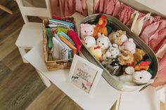 a basket filled with lots of stuffed animals sitting on top of a white table next to a wooden chair