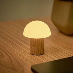 a wooden table with a small mushroom light on it and a cell phone next to it