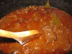 a wooden spoon stirring some food in a pot