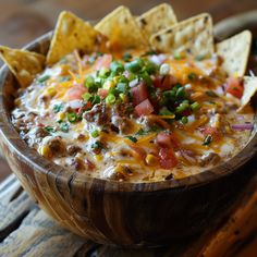 a wooden bowl filled with nachos and chips