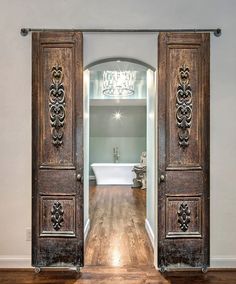 an open door leading to a bathroom with a tub and chandelier in the background