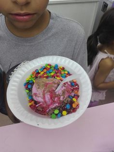 a young boy holding a paper plate with a doughnut covered in sprinkles