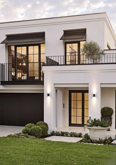 a white two story house with black shutters and balconies on the second floor