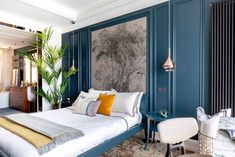 a bedroom with blue walls, white bedding and artwork on the wall behind it