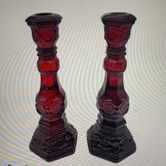 two red glass candlesticks sitting next to each other