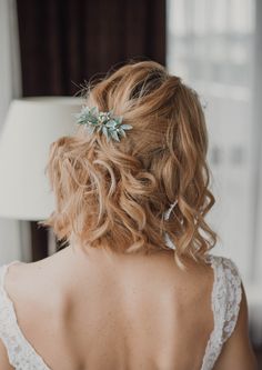 the back of a woman's head wearing a wedding dress and hair comb with leaves on it