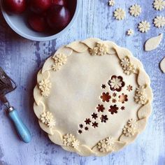 a pie sitting on top of a table next to a bowl of cherries